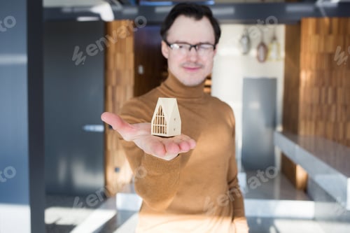 Preview: Real estate agent, modern house model in male hands. concept of buying, selling or building housing.