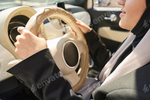 Preview: Arab woman driving a car with a beige interior