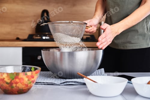 Preview: Woman in kitchen cooking a dough. Hands pour flour into a bowl