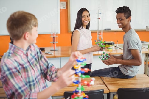 Preview: Happy school kids experimenting molecule model in laboratory