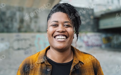 Preview: Happy African woman smiling in front of a camera in the city