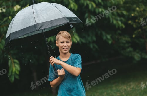 Preview: Teen Boy Smiles With Umbrella in Rainy Weather