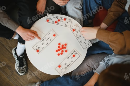 Preview: Friends playing board game with numbered cards and red markers