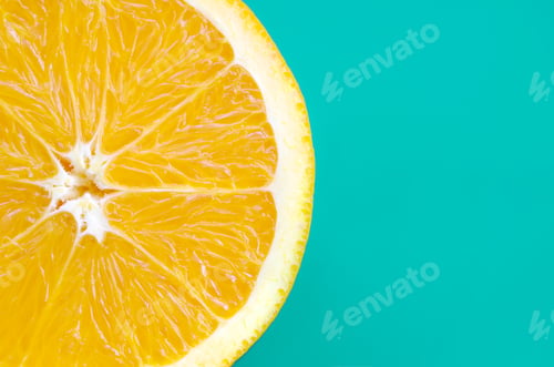 Preview: Top view of a one orange fruit slice on bright background in turquoise green color. A saturated