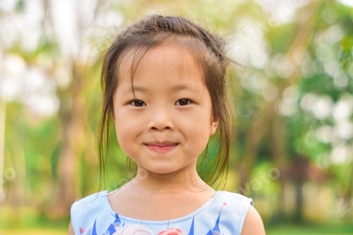 Preview: Close-up portrait of smiling beautiful little girl in a summer green park.
