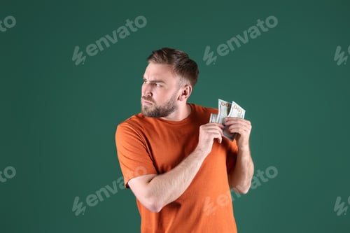 Preview: Greedy young man hiding money on green background