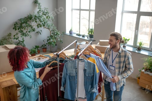 Preview: Young girl and man sorting clothes on trempels.