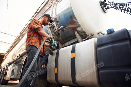 Preview: Young truck driver in casual clothes is refueling the vehicle