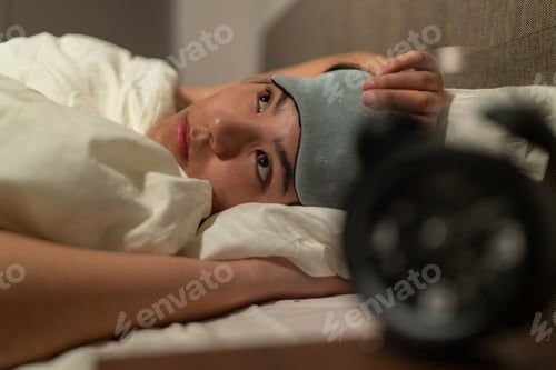 Preview: Stressed young woman suffering from insomnia lying in bed at night
