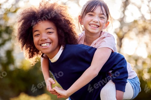 Preview: Portrait Of Smiling Boy Giving Girl Piggyback Outdoors In Garden