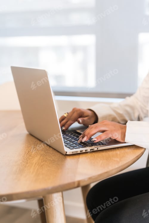 Preview: Woman's hands working on laptop at wooden table