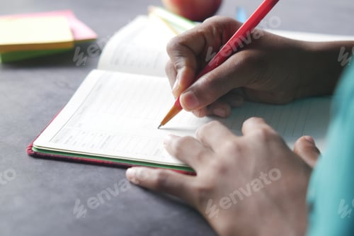 Preview: rear view of child boy hand writing on notepad.