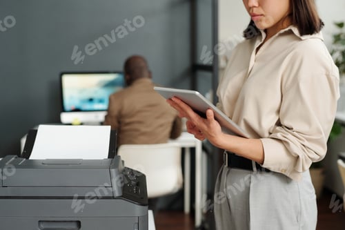Preview: Focus on tablet held by young elegant businesswoman computing in office
