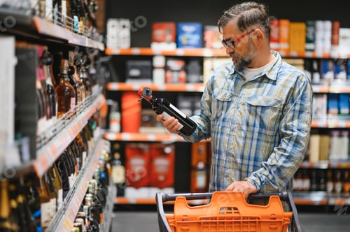 Preview: Man in a supermarket choosing the right wine