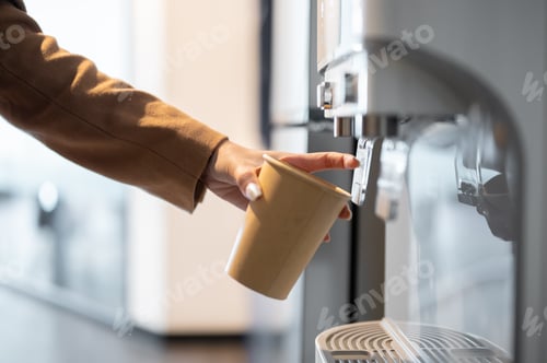 Preview: Close up businesswoman or office worker's hand holding paper cup getting hot water to making coffee
