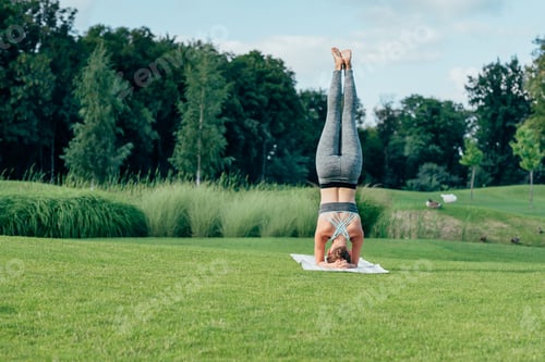Preview: athletic woman performing Feathered Peacock yoga Pose while exercising in park