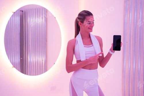Preview: Young female coach showing her phone with blank screen for fitness app