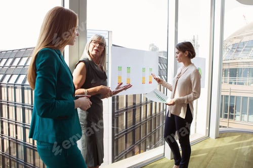 Preview: Three professional women discussing a chart in a modern office setting.