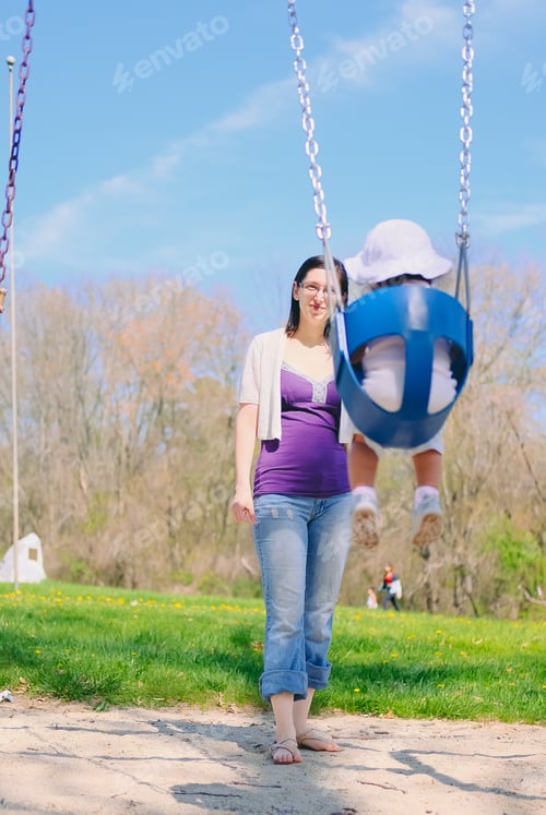 Preview: Mother and diverse toddler girl bonding together as a family on a nice summer day at playground park