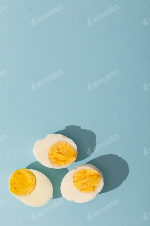 Preview: Directly above view of copy space with fresh boiled white egg halves over blue background