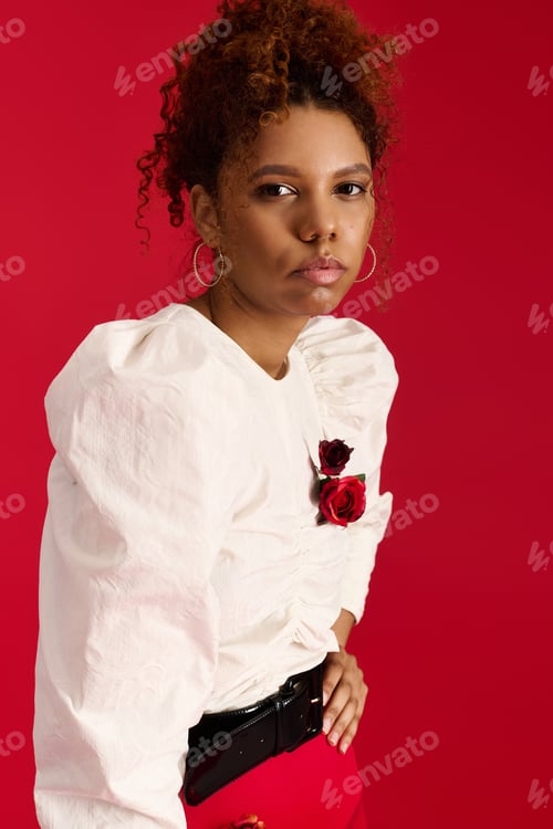 Preview: Young woman showcases fashionable style against a vibrant red backdrop in a chic setting