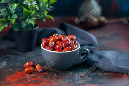 Preview: Front close view of fresh raw silverberry fruits inside and outside of a gray cup and flower pot on