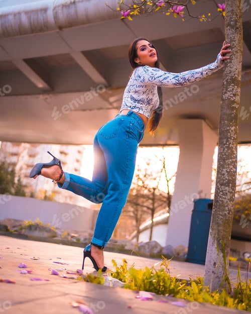 Preview: A brunette Latina girl in a city park next to a tree with pink flowers. Spring lifestyle