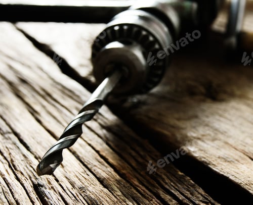 Preview: Old drill on a wooden background.