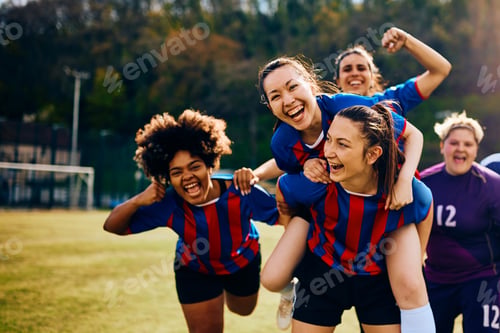 Preview: Cheerful female players celebrating scoring a goal during soccer match on playing field.
