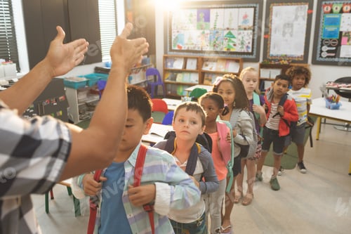 Preview: Front view of school kids standing and forming a queue in classroom at school