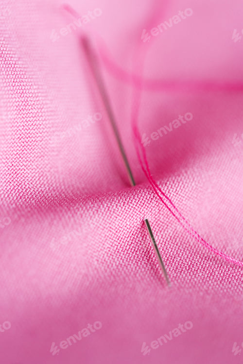 Preview: sewing needle with thread stuck into pink fabric