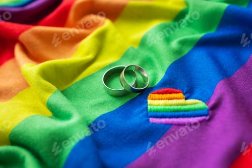 Preview: Two wedding rings on a lgbt rainbow flag along with heart embroidered. homosexual marriage. LGBT