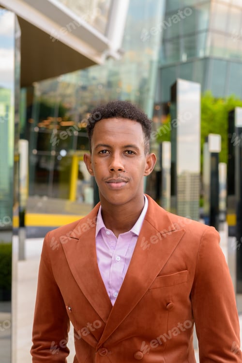Preview: Portrait of handsome black African businessman outdoors in city