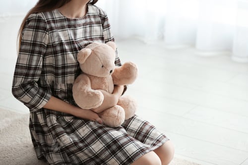 Preview: Upset girl with toy indoors, closeup. Space for text