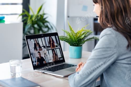Preview: young business woman making video call with computer while talking with earphone sitting in office.