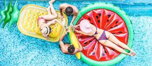 Preview: Happy friends having cheering with cocktails in swimming pool party