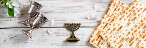 Preview: Happy Passover flatlay. Jewish matzo bread and wine glasses on white wooden background.