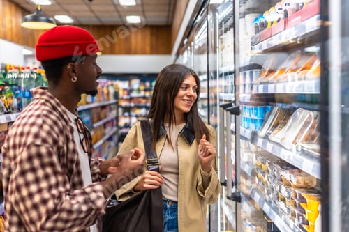 Preview: Diverse couple grocery shopping choosing food items in supermarket aisle