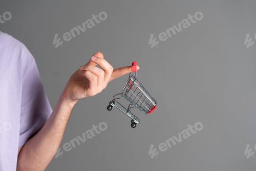 Preview: a human hand holding an empty shopping cart as the symbol of online shopping and e-commerce