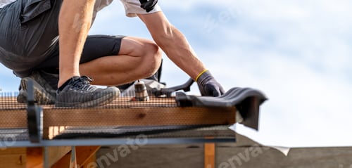 Preview: work at heights, worker builds a roof from ceramic tiles