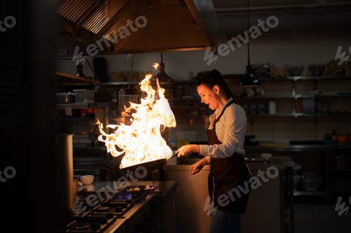 Preview: Professional chef preparing meal, flambing indoors in restaurant kitchen