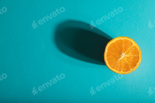 Preview: Ripe cut orange on blue pastel background. Top view, copy space, hard light.