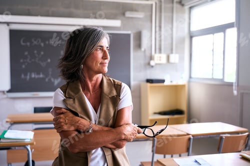 Preview: A teacher stands alone in an empty classroom, gazing thoughtfully out of the window