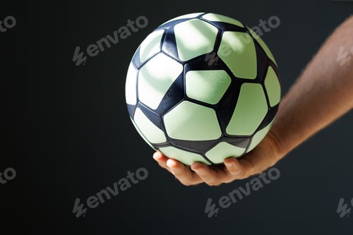 Preview: green black ball for handball in the athlete's hand on a black background