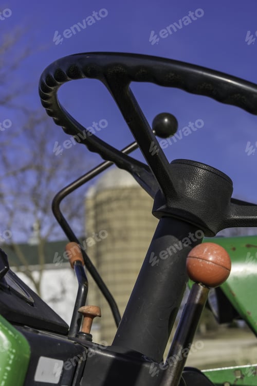 Preview: In Control On The Farm: Closeup Of Steering Wheel And Shift Gears Of Tractor Near Silo And