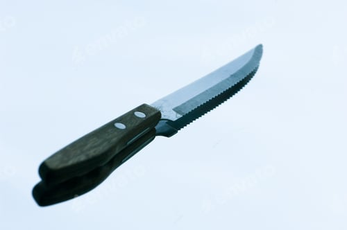 Preview: Serrated Knife And Its Shadow Against Light Blue Sky