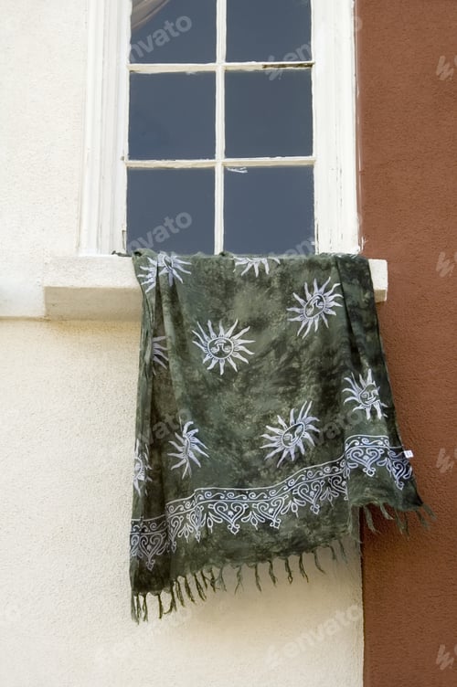 Preview: Fringed Towel With Sun Pattern Hanging Off Ledge Of Plain Window