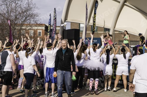 Preview: Kalamazoo, Michigan, Usa - April 12, 2014: A Grinning Man Walks Away With Freebies While Runners