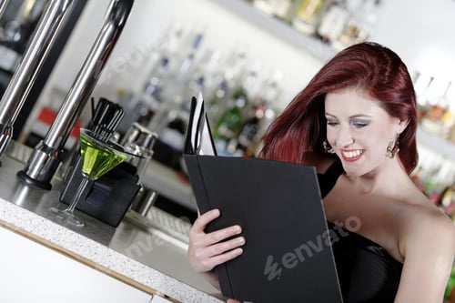 Preview: Attractive Young Woman Reading From A Wine List At The Bar.