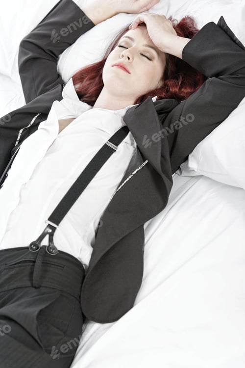 Preview: Professional Business Woman Lying On A Bed After A Long Day In The Office Nursing A Headache.